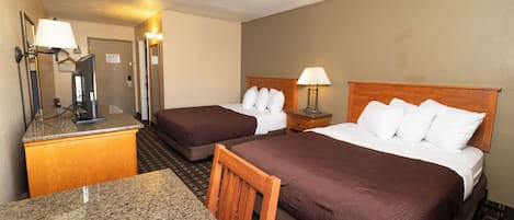 A hotel room with two beds, a desk, and a mirror.