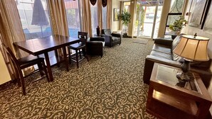 A hotel lobby with a dining area, seating, and a patterned carpet.
