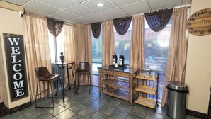 A small, cozy room with a 'WELCOME' sign, a coffee station, a clock, and a trash can.