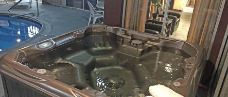 A hot tub with a towel, a pool, and outdoor seating.