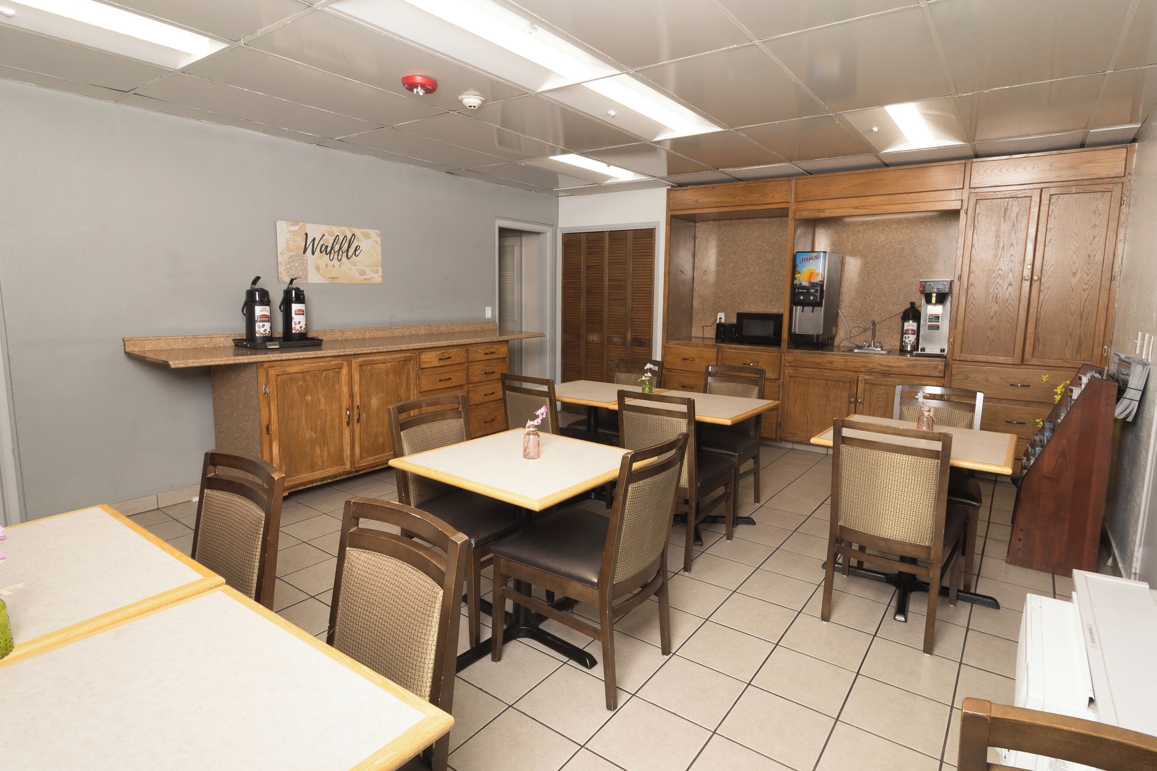 A cafe interior with wooden furniture, a coffee machine, and a waffle bar sign.