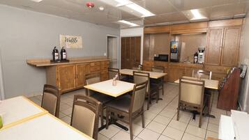 A cafe interior with wooden furniture, a coffee machine, and a waffle bar sign.