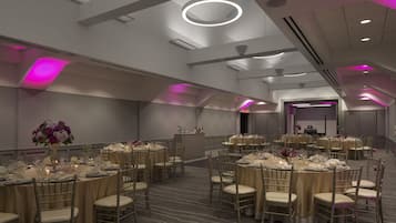 A spacious banquet hall with round tables, chairs, and a central bar area.