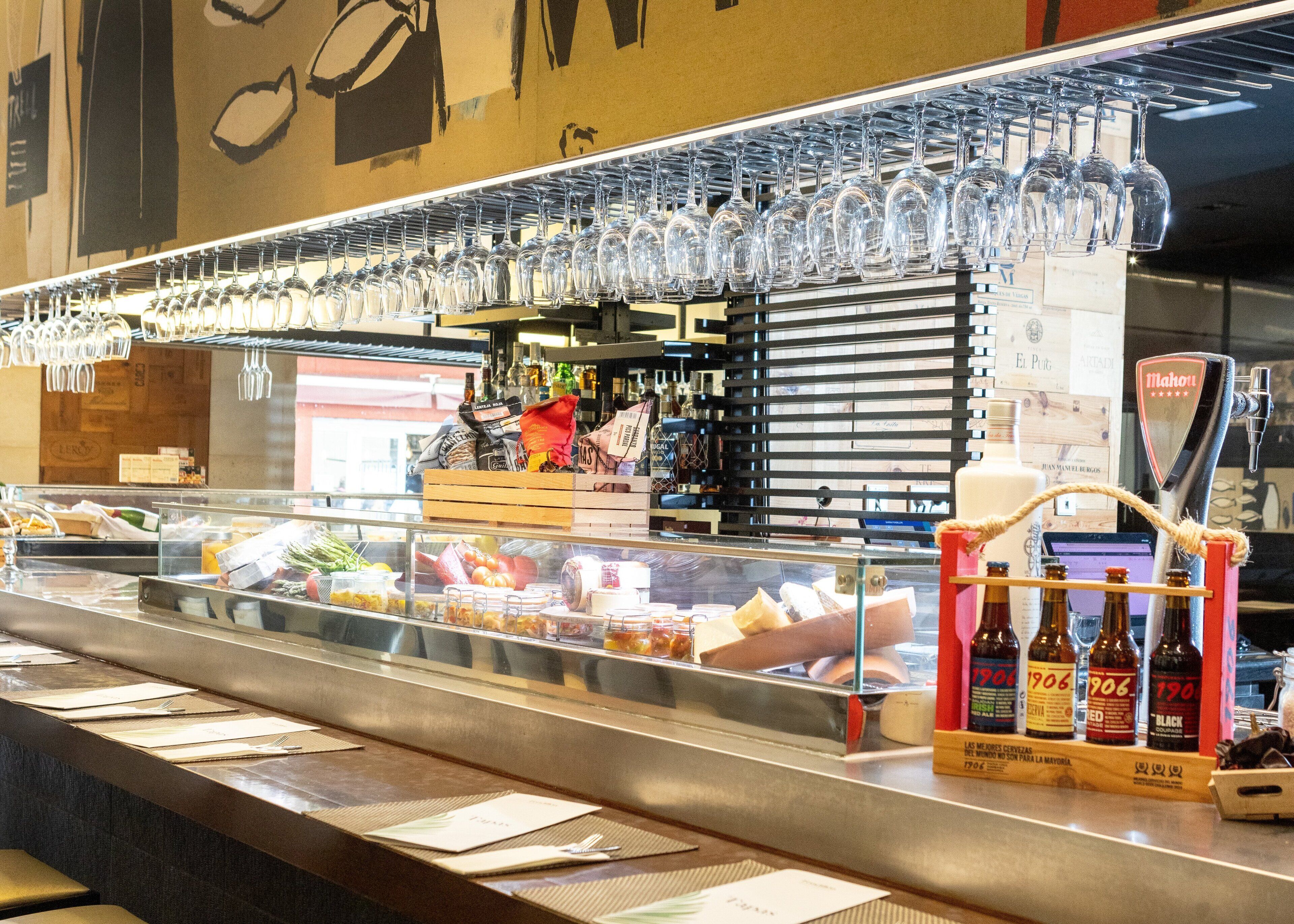 Zona de bufé con un expositor de vidrio que contiene diferentes alimentos y una selección de bebidas embotelladas.