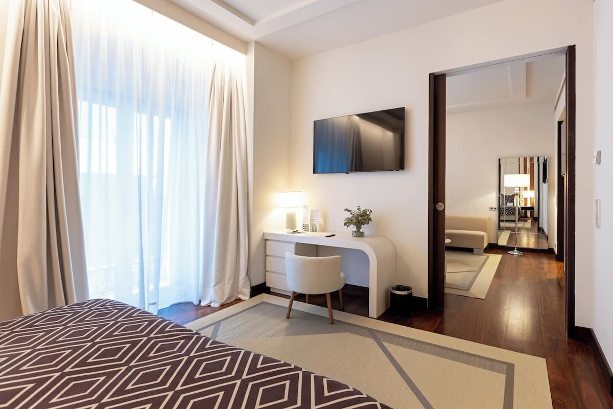 Une chambre d’hôtel moderne dotée d’un grand lit, d’un bureau avec une lampe, d’une télévision à écran plat et d’un grand miroir.