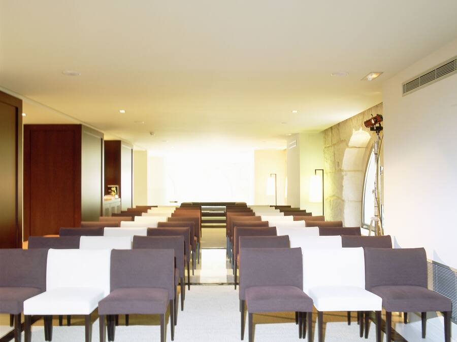 A conference room with rows of chairs, a podium, and a staircase leading to an upper level.