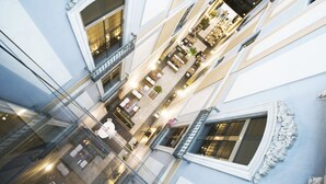 Un centro comercial de varios niveles con barandillas de vidrio, detalles arquitectónicos ornamentados y múltiples plantas.