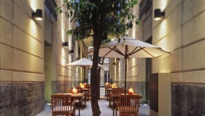 Un patio con mesas, sillas, un árbol y velas.