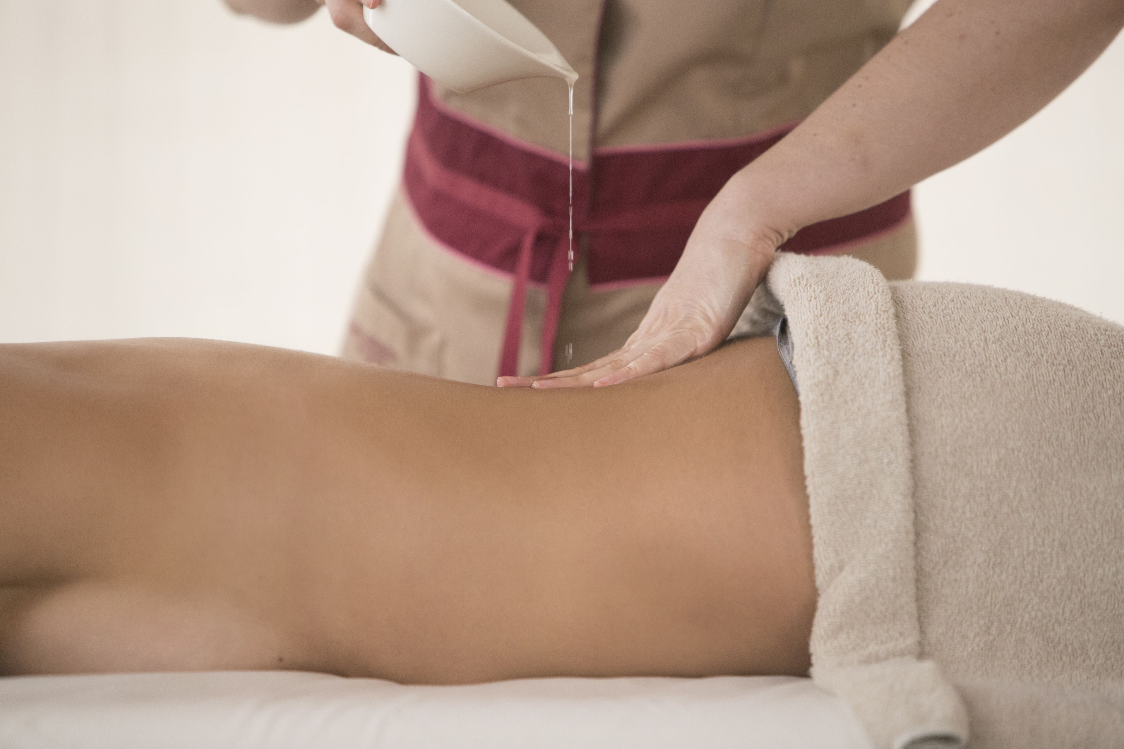 A person receiving a massage with a towel covering the lower body.