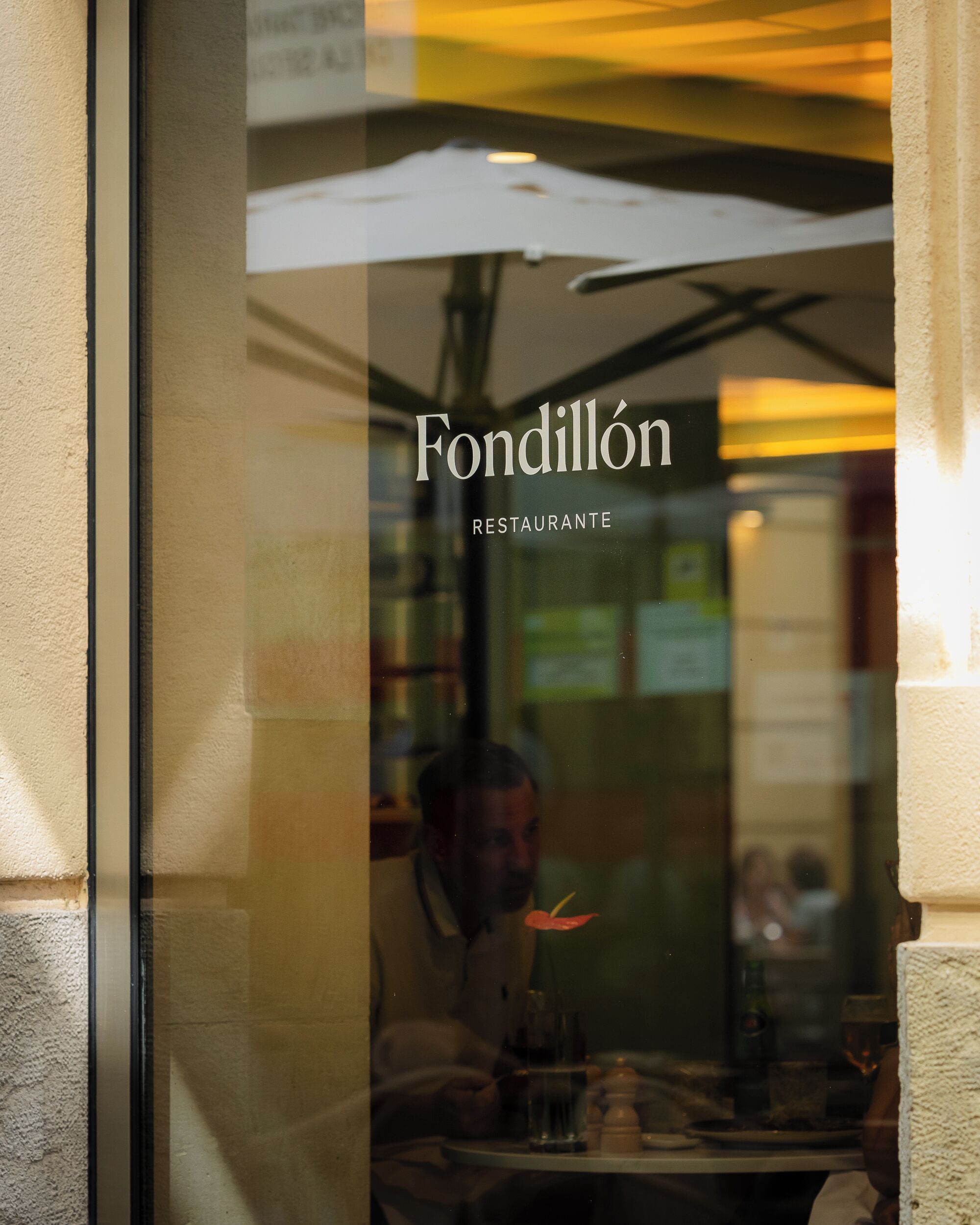 Een restaurantraam met de naam 'Fondillón Restaurante' en een reflectie van een persoon van binnen.