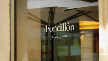 Een restaurantraam met de naam 'Fondillón Restaurante' en een reflectie van een persoon van binnen.