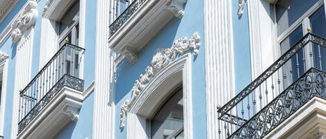 Fachada de edificio con balcones ornamentados y detalles arquitectónicos clásicos.