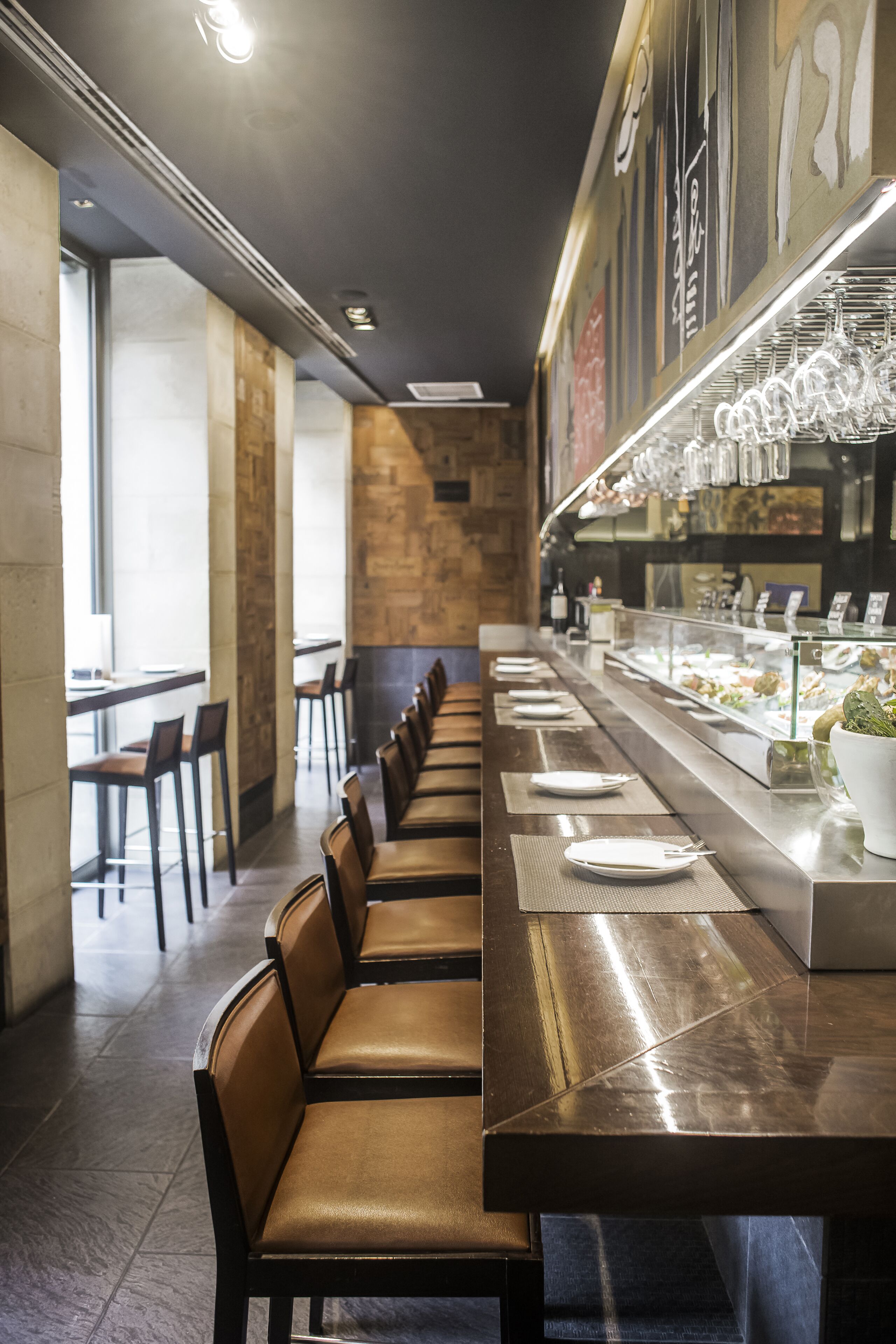 A long dining table with chairs, a glass display case with food items, and a wall with abstract art.