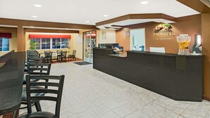 A hotel reception area with a reception desk, chairs, and a large window. - Microtel Inn & Suites by Wyndham Holland (Holland)