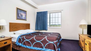 A hotel room with a bed, a wooden headboard, a window with curtains, a desk with a lamp, and a TV on a wooden cabinet.