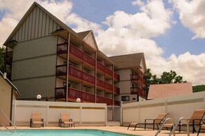 A hotel with a pool area, multiple balconies, and lounge chairs.