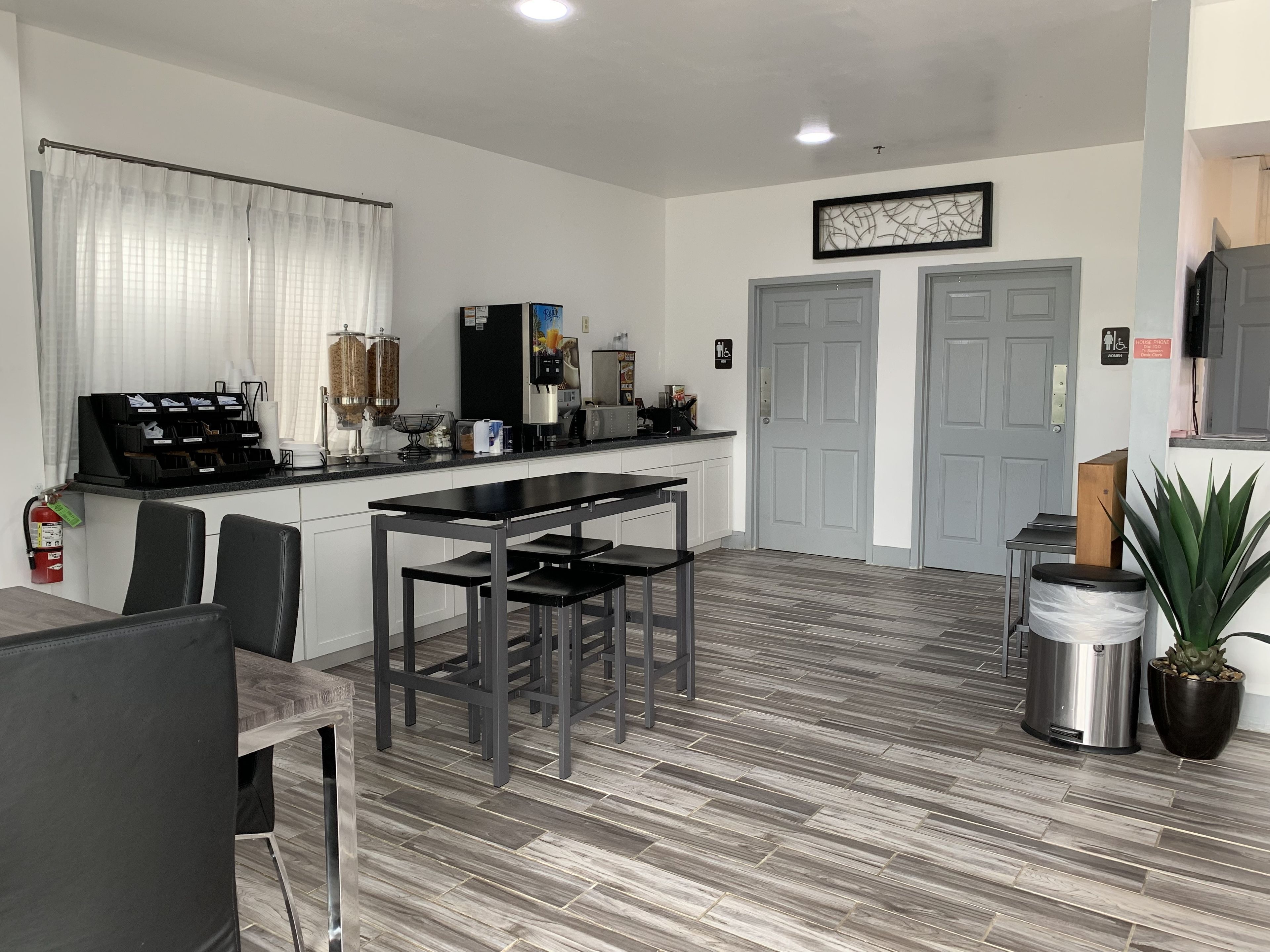 Una cocina moderna con comedor, armarios blancos y piso gris.