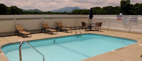 A swimming pool with lounge chairs and a view of mountains.