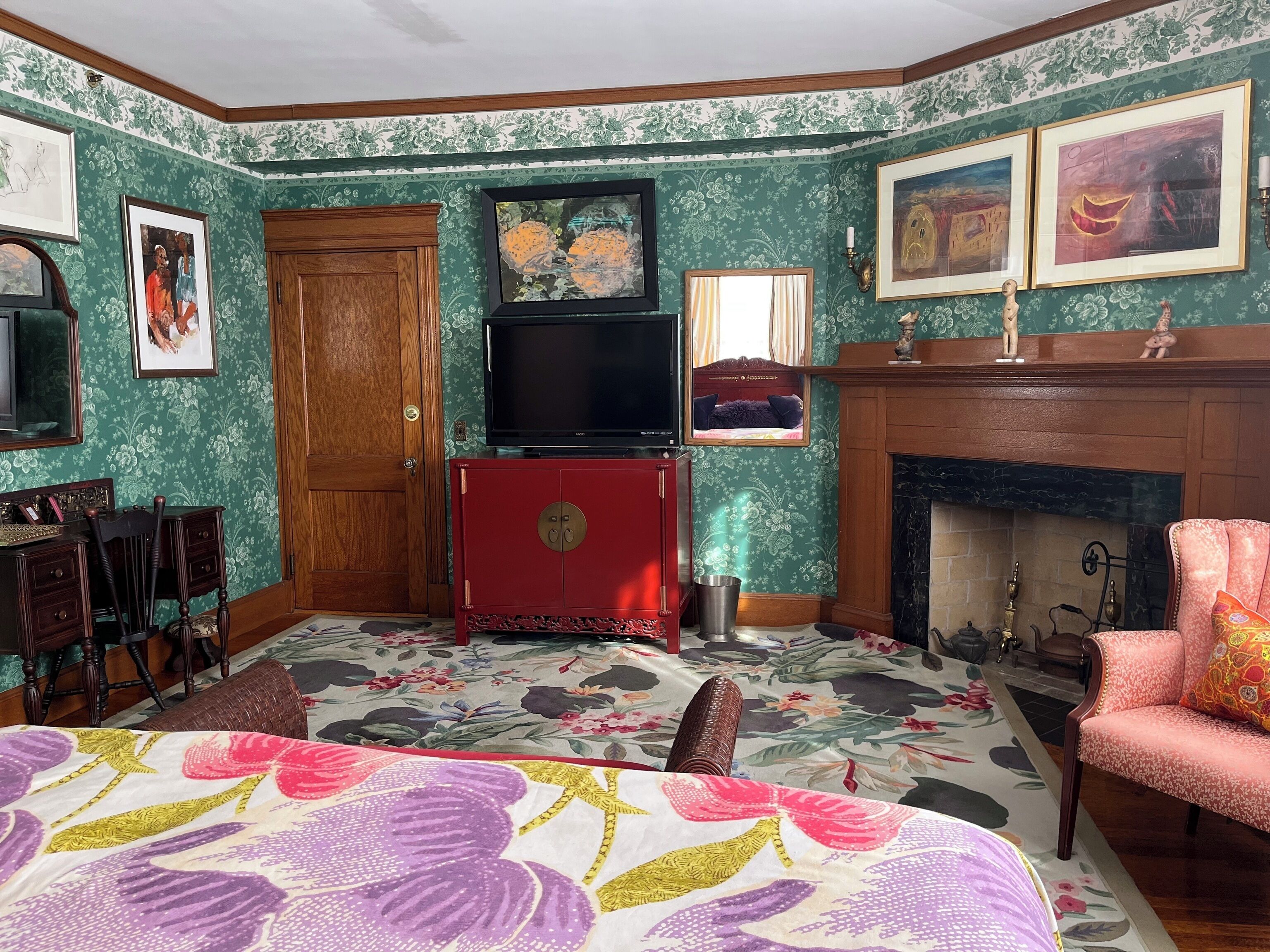 Ein Zimmer mit einem Bett, einem Fernseher, einem Kamin und einer Tür.