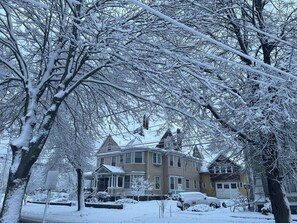 A two-story house with a snow-covered roof and a porch.