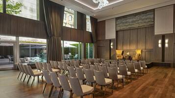 A conference room with rows of chairs, large windows, and a view of outdoor seating.