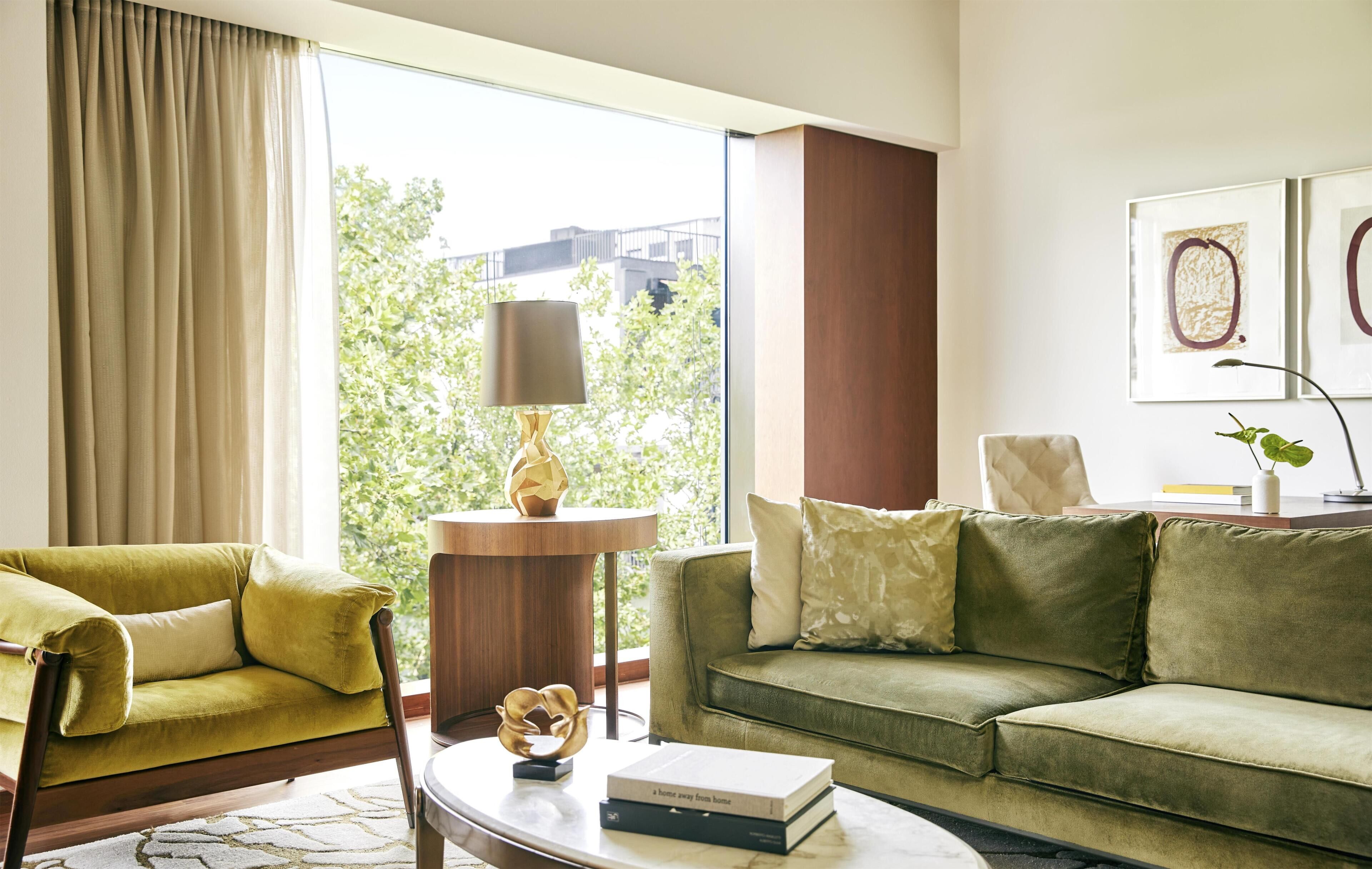 Una sala de estar moderna con sofá, sillón, lámpara y libros.