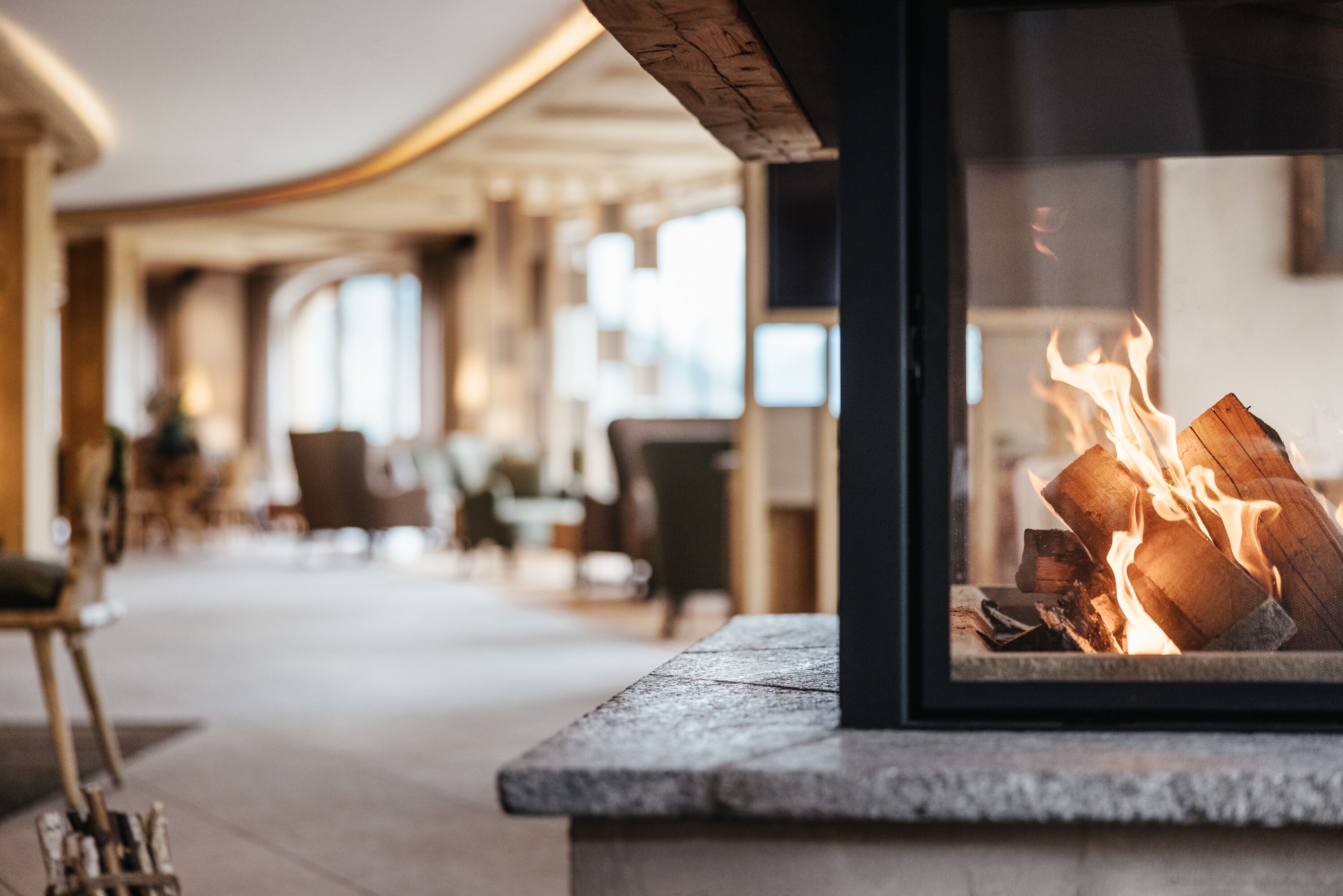 A modern interior with a fireplace, seating area, and large windows.