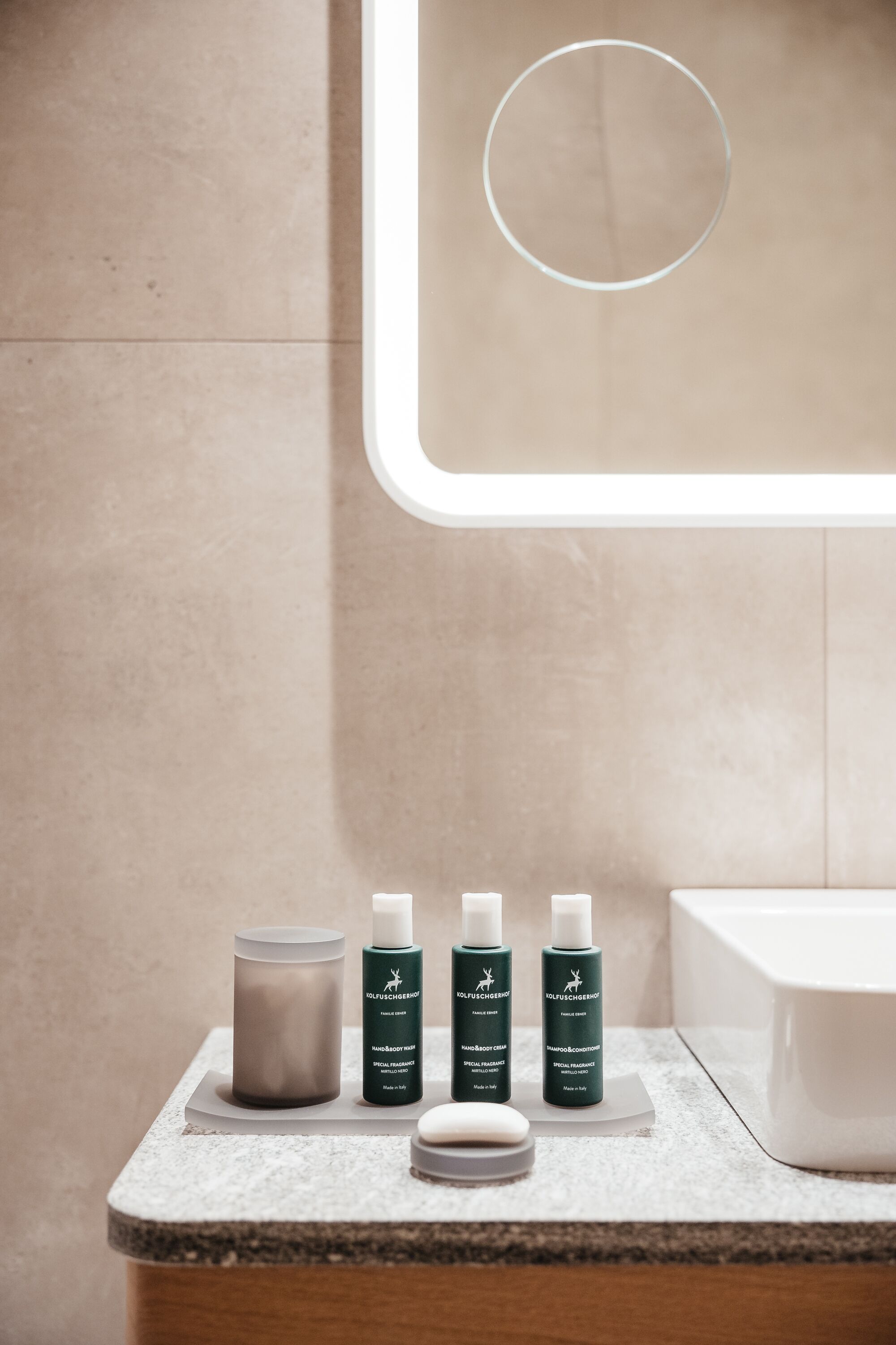 A bathroom vanity with a mirror, a white sink, and three bottles of hand soap and body wash.