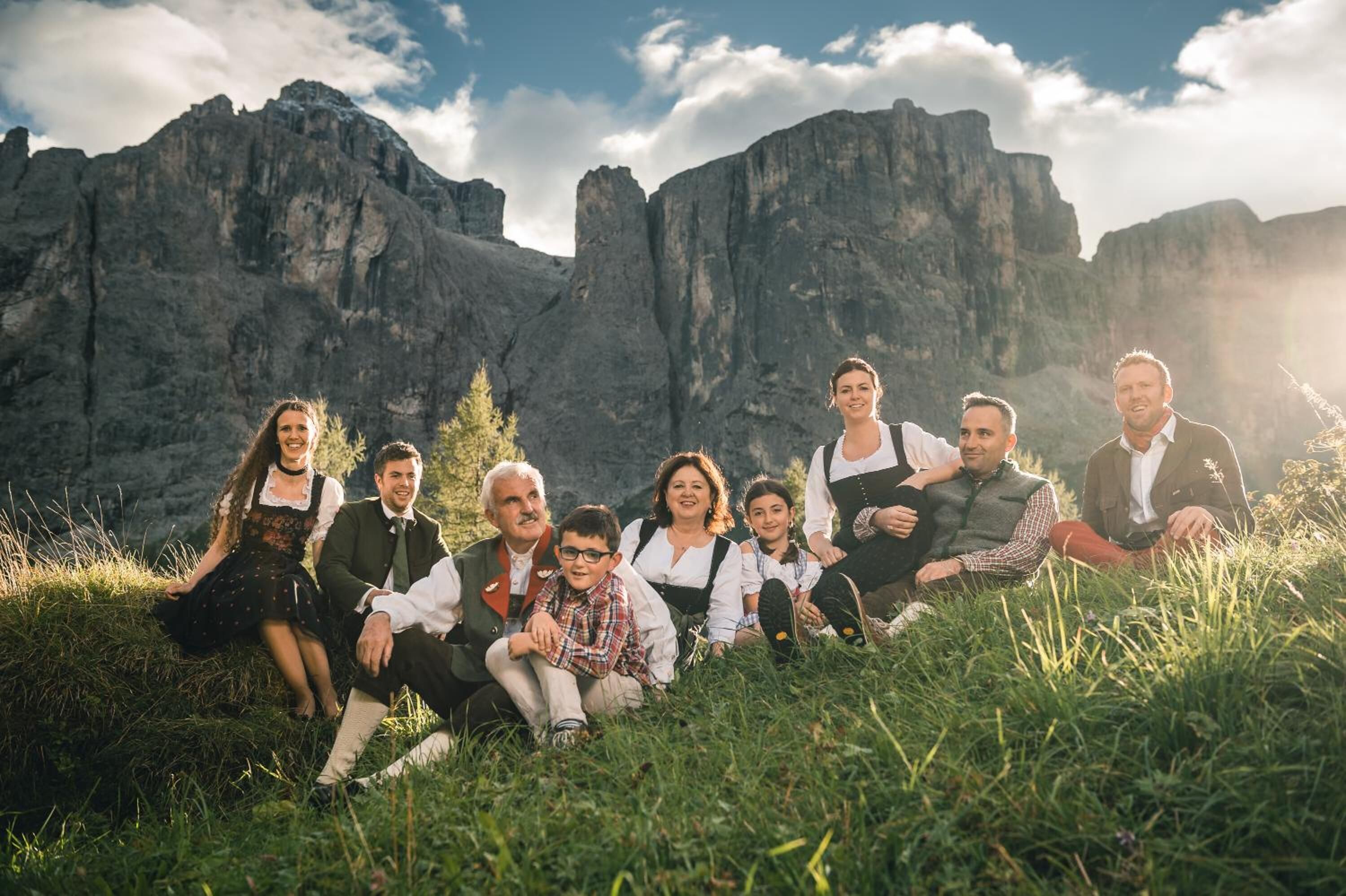 Un grupo de personas sentadas sobre la hierba, con montañas al fondo.