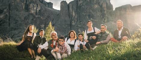 Un grupo de personas sentadas sobre la hierba, con montañas al fondo.