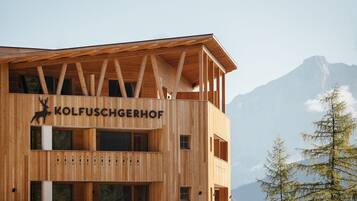 A wooden building with the name "KOLFUSCHGERHOF" and a deer logo. It has multiple windows and balconies.