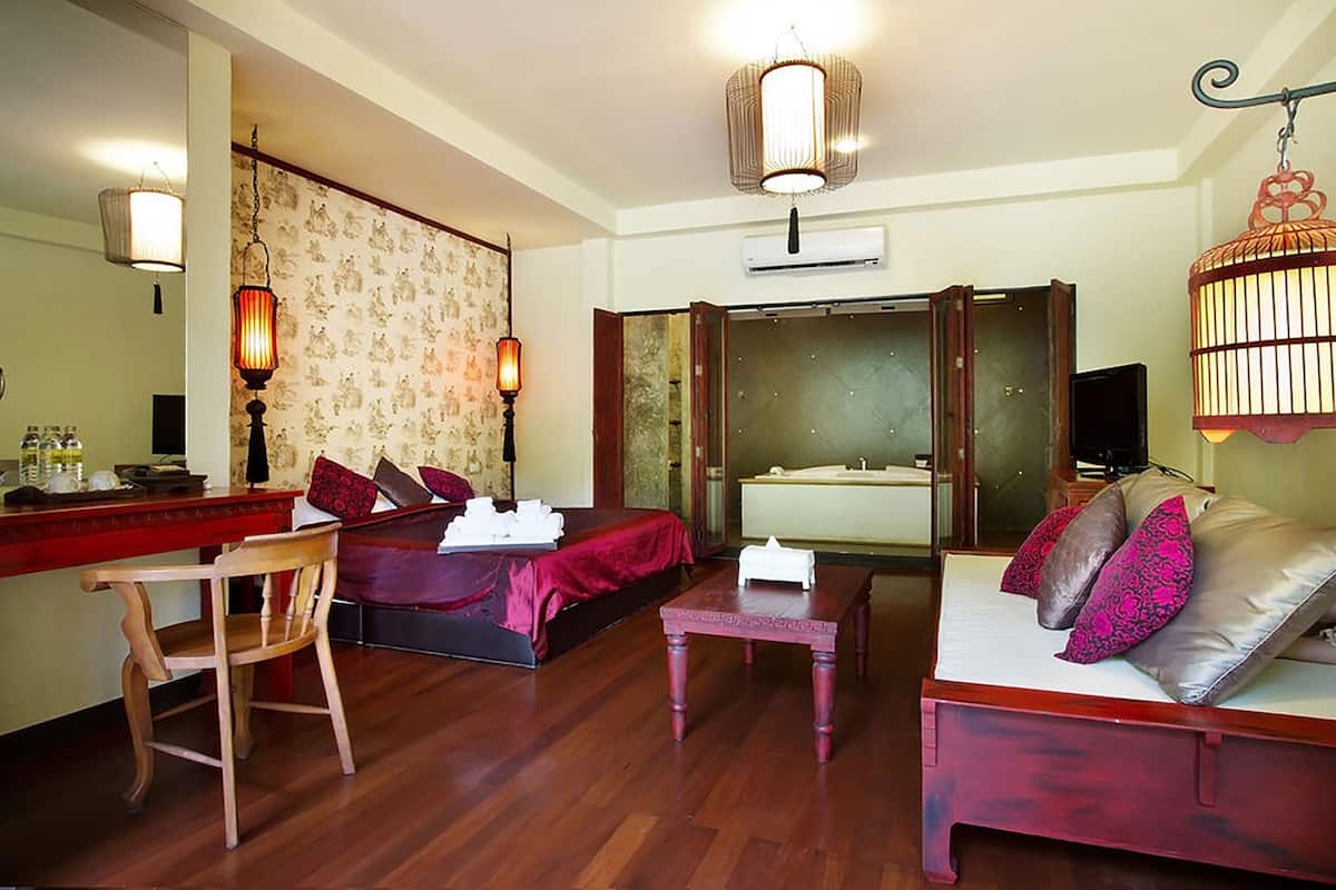 A hotel room with a bed, a sofa, a desk, and a bathroom.