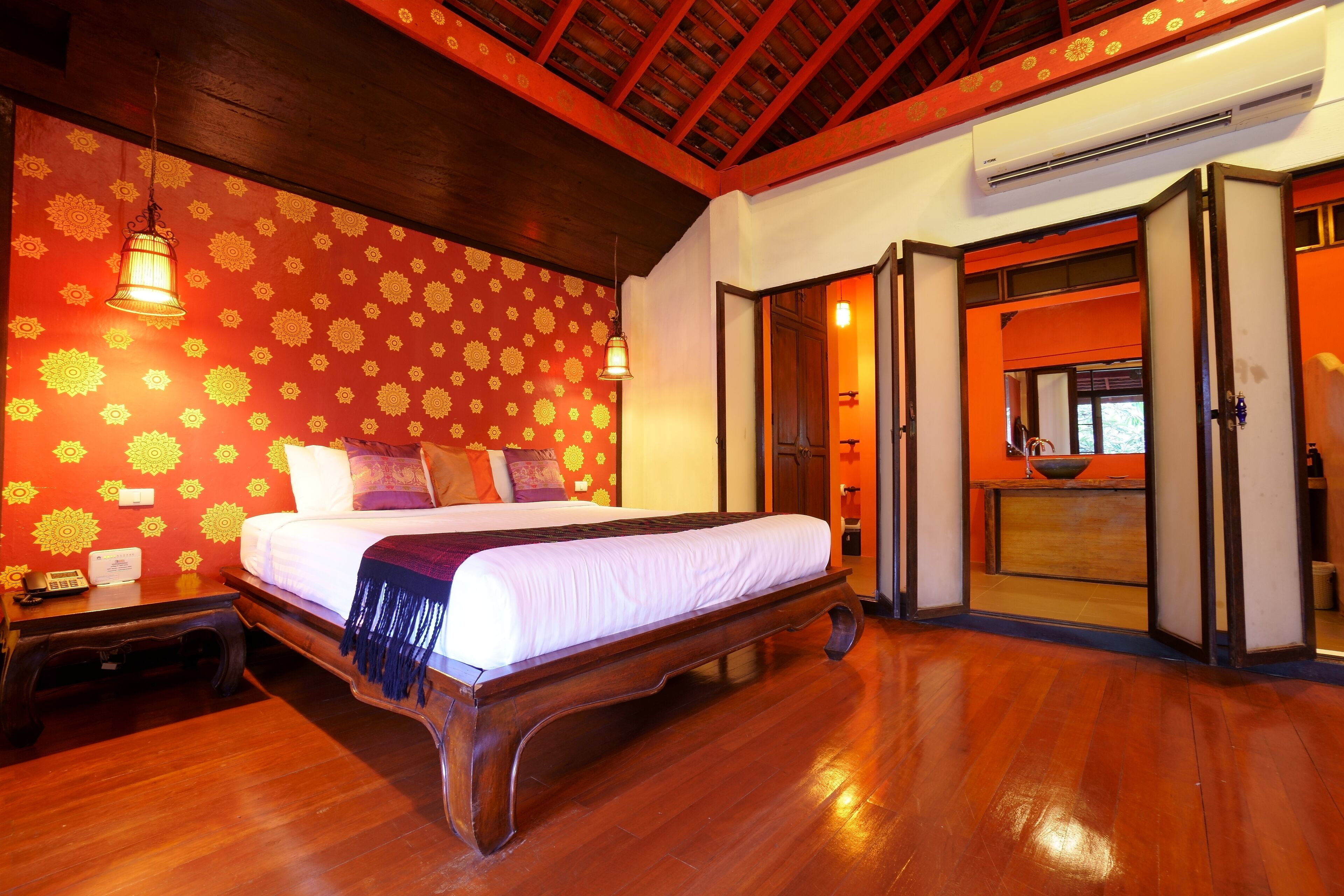 A spacious room with a large bed, wooden flooring, and a patterned wall.