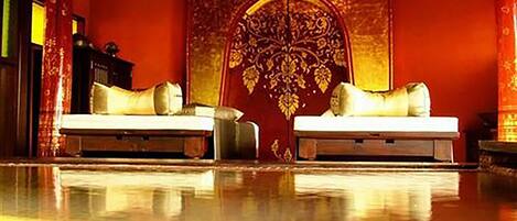 A room with two beds, a large ornate wall decoration, and a polished floor.