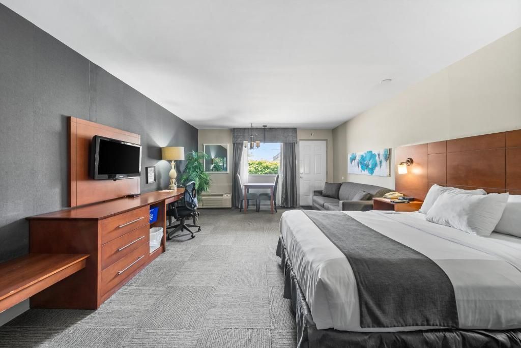 A hotel room with a bed, desk, TV, and a view of the outdoors.