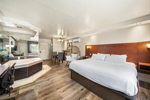 A modern hotel room with a large bed, a sitting area with a chair and table, a small desk, and a large mirror. - Hotel - Motel Coconut (Trois-Rivieres)