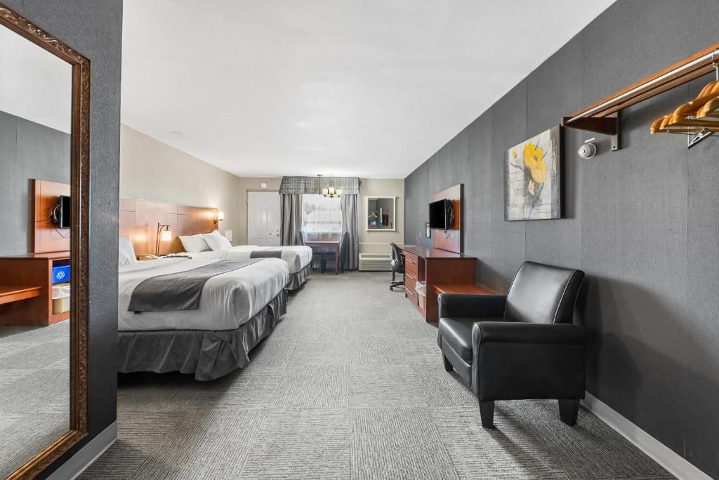 A hotel room with two beds, a desk, a chair, a mirror, and a painting on the wall.