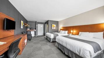 A hotel room with two beds, a desk, a chair, a television, and a wardrobe.