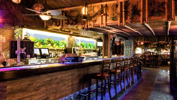 A bar area with wooden bar counters, stools, and a decorative ceiling. - Hotel - Motel Coconut (Trois-Rivieres)