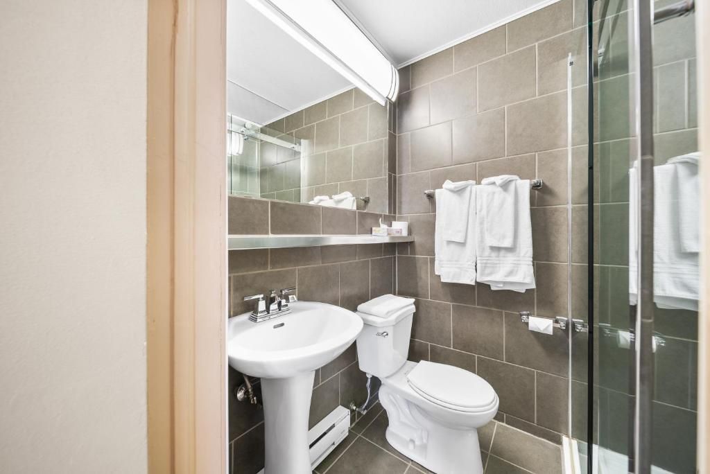 A modern bathroom with a sink, toilet, and glass shower enclosure.