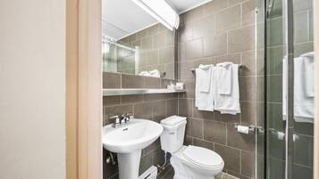 A modern bathroom with a sink, toilet, and glass shower enclosure.