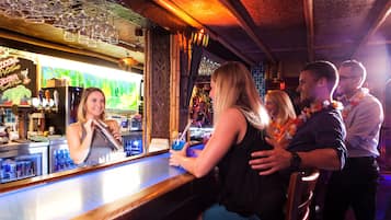 A bar area with a bartender, a counter, and a tropical-themed decor.