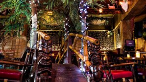 A restaurant interior with wooden decor, hanging plants, and a staircase. - Hotel - Motel Coconut (Trois-Rivieres)