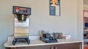Une machine à café, un tableau affichant le menu et un comptoir équip é d’un moulin à café et d’ustensiles.
