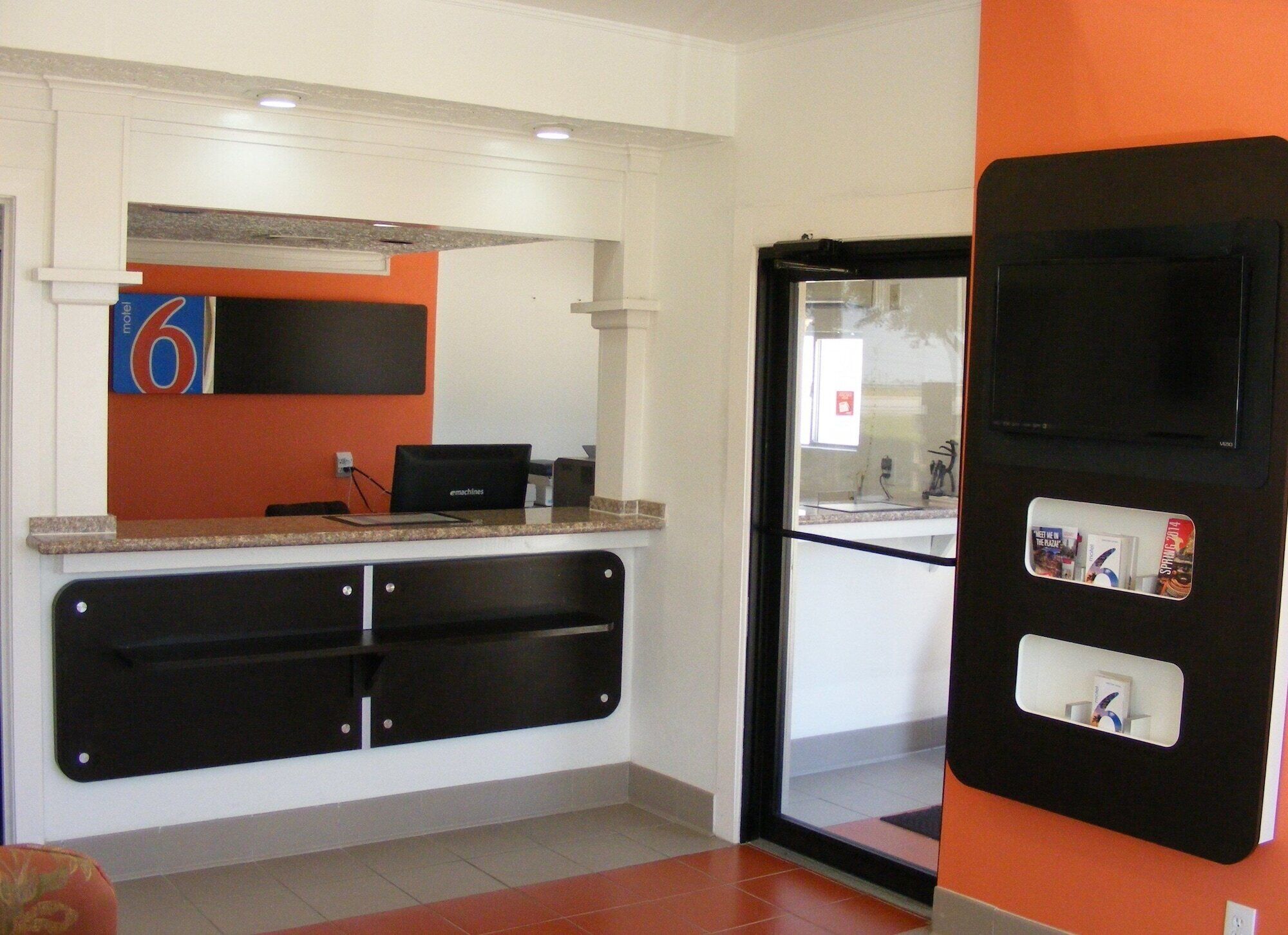 A reception area with a counter, a black desk, and a door with a glass panel.