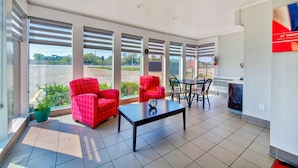Un espace intérieur moderne doté de grandes fenêtres, de chaises rouges, d’une table noire et offrant une vue sur l’extérieur.