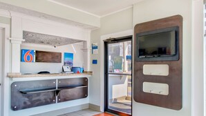 Un espace d’accueil comprenant un comptoir, un téléviseur et une porte donnant sur l’extérieur.