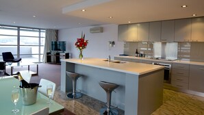 A modern kitchen with a large island, bar stools, and a dining area with a table and chairs. - Zero Davey Boutique Hotel (Hobart)