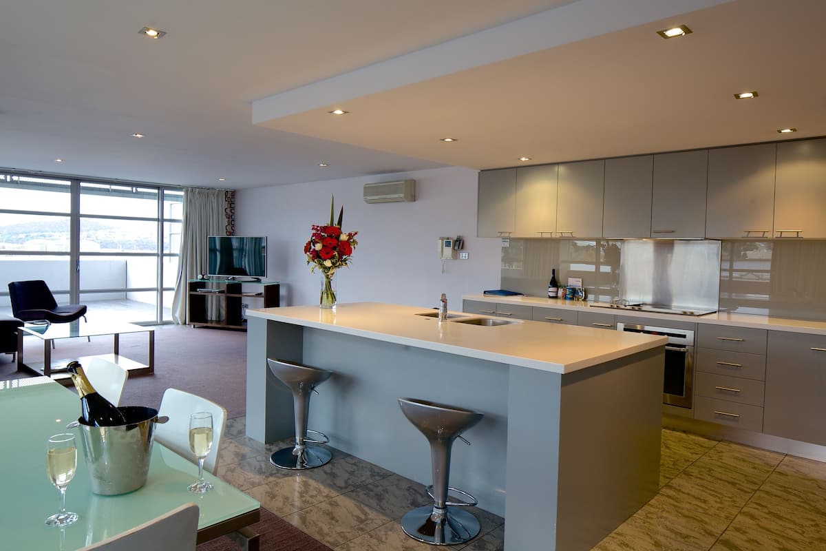 A modern kitchen with a large island, bar stools, and a dining area with a table and chairs.
