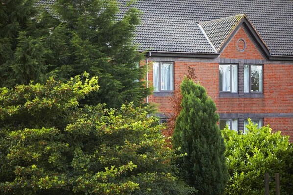 A brick house with a tiled roof, surrounded by dense greenery. - Travelodge Washington A1 Northbound (Chester-le-Street)